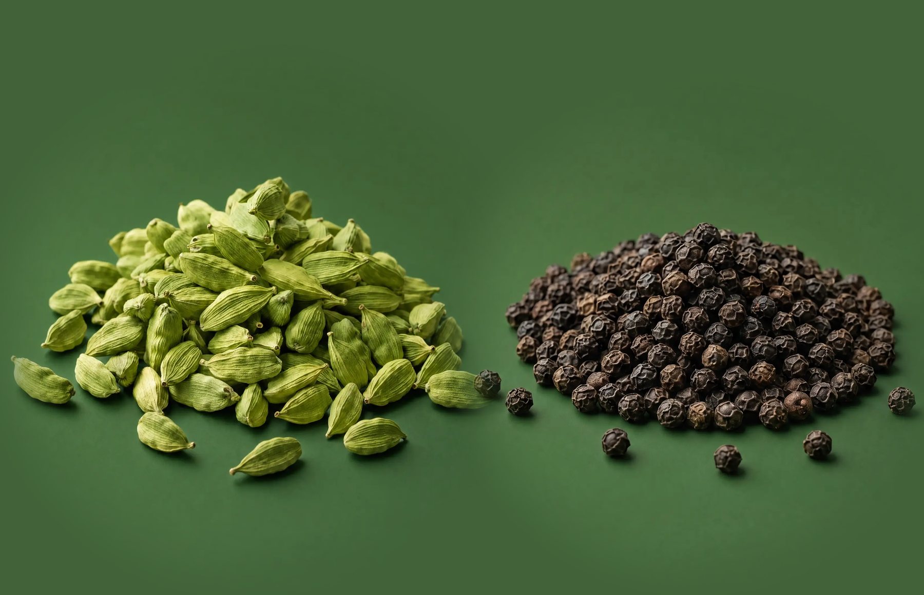 Green cardamom pods and black peppercorns from the High Range estate, side by side